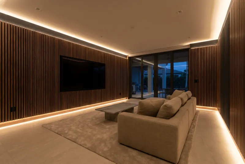 Home theater with walnut-finish acoustic slat panels and warm LED along floor and ceiling